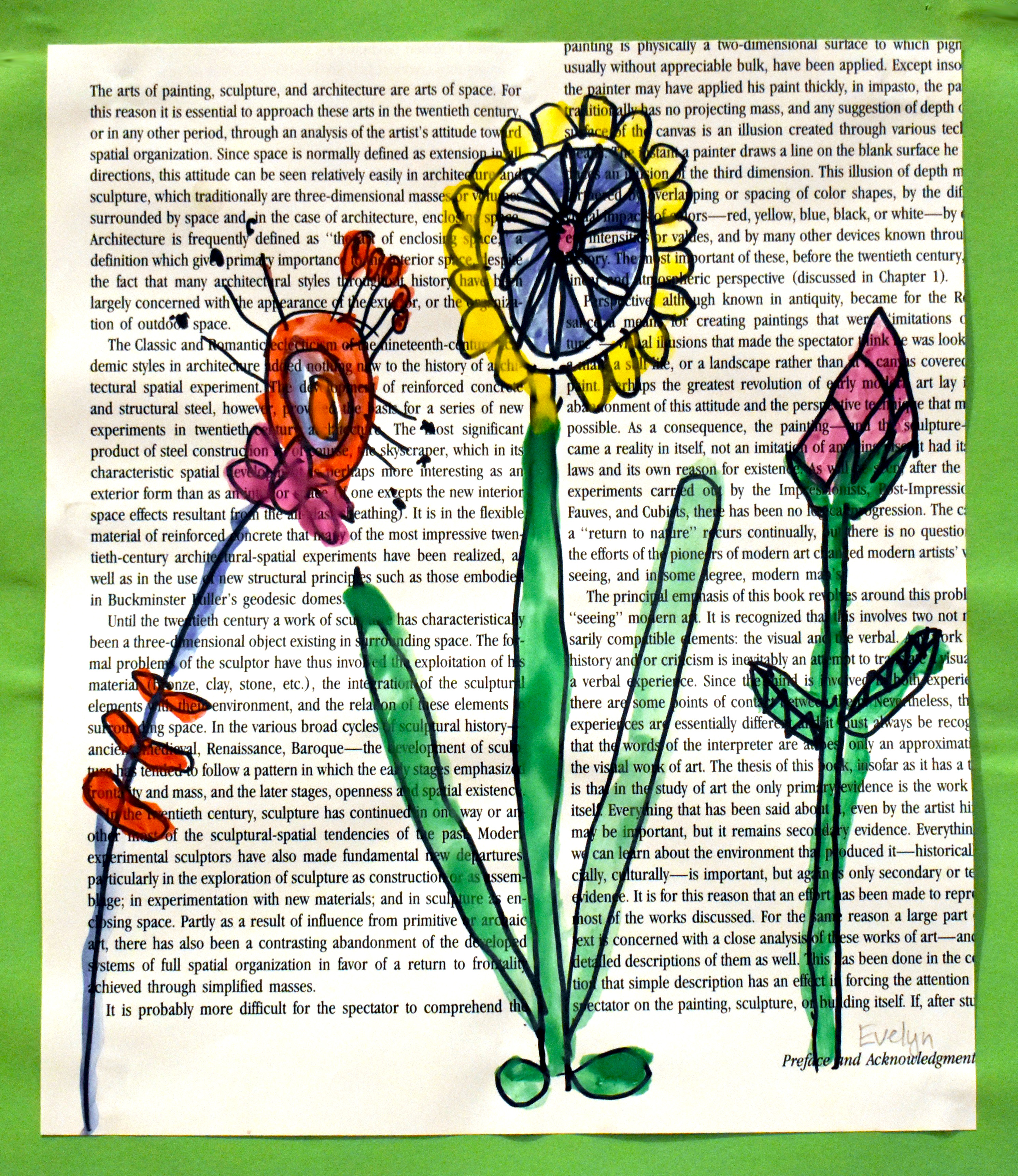 Three multicolored flowers on the page of a book covered in text discussing art-making. Mixed media: Ink and water color